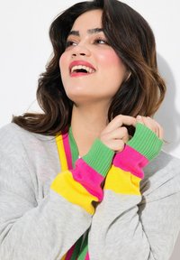 Lichtgrijze cardigan met geribde mouwen in roze, groen en geel. Met een ontspannen pasvorm en levendige accentkleuren.