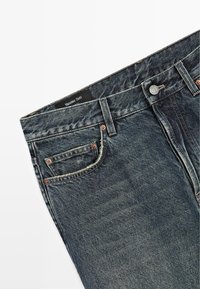 Jeans in denim blu scuro con una texture sbiadita, design a cinque tasche, rivetti color rame e un'etichetta nera con la scritta "Massimo Dutti".