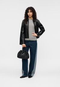 Μαύρο δερμάτινο μπουφάν, ριγέ τοπ, παντελόνια τζιν με φαρδιά μπατζάκια και αντίθετες πλαϊνές ρίγες, και μαύρη τσάντα με σούρες. Ομαλές υφές, απλή σχεδίαση.