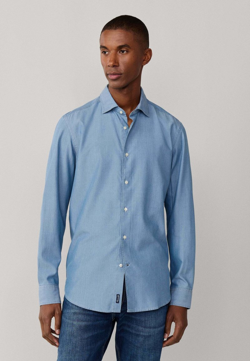 Camicia azzurro chiaro a maniche lunghe con bottoni, realizzata in cotone, con colletto classico, patta frontale con bottoni bianchi e un design leggermente aderente.