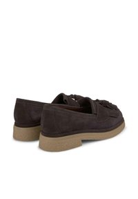 Scarpe slip-on in suede marrone scuro con suola in gomma leggera marrone chiaro testurizzata. Le caratteristiche includono un dettaglio frange decorativo sulla parte anteriore.