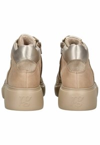 Beige Ankle Boots aus Leder, mit einem glatten metallischen Akzent an der Ferse, seitlichen Reißverschlüssen und einer dicken, strukturierten Sohle.