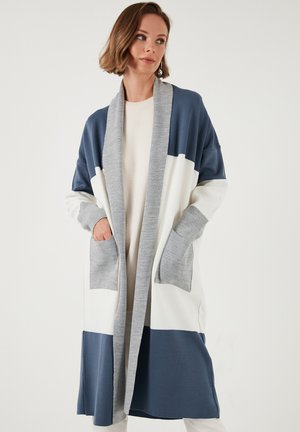Cardigan lung în nuanțe de albastru marin, alb și gri. Prezintă un guler tip șal, mâneci lungi și două buzunare în față. Textură moale și netedă.