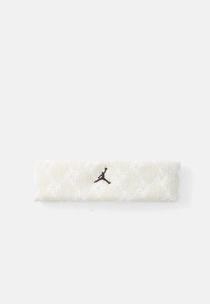 Beżowa dzianinowa opaska na głowę z subtelnym białym wzorem i czarnym haftowanym logo Jumpman umieszczonym centralnie na białym tle.