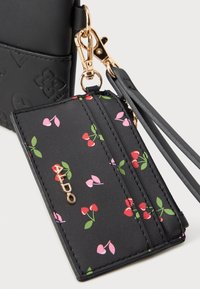 Črn kartica iz umetne usnje s češnjevim vzorcem in rožnatimi detajli, opremljen z zlatim logotipom in sponko za enostavno prenašanje.