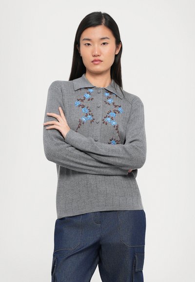 Šedý pletený svetr s límcem, zdobený modrou květinovou výšivkou na přední straně. Dlouhé rukávy a zapínání na knoflíky u krku.