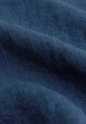 Granatowy materiał o gładkiej fakturze i subtelnym połysku, z delikatnym blaskiem i skomplikowanymi wzorami tkackimi widocznymi z bliska.