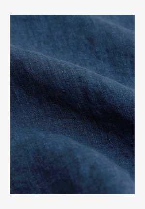 Jūras spēku zilas krāsas audums ar gludu tekstūru un maigu spīdumu, ar viegli redzamām sarežģītām auduma struktūrām tuvplānā.