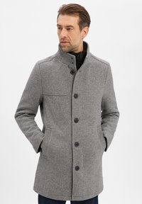 Grijze visgraatjas met hoge kraag, knoopsluiting en zijzakken. Zachte textuur en gestructureerde pasvorm zorgen voor extra warmte en stijl.