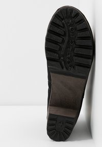 Semelle d’une botte noire montrant des crampons profonds et le nom de la marque « GOLDTOX » embossé sur la semelle en caoutchouc.