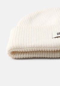 Berretto a coste di colore bianco sporco con risvolto e un discreto etichetta del marchio. Texture morbida con dettagli di cucitura visibili.