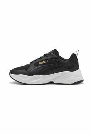 Baskets Puma noires avec semelle blanche épaisse, design à lacets, tige en mesh et cuir, et logo Puma beige sur le côté.