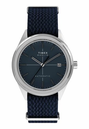 Timex Marlin automatic watch with dark blue dial, silver hour markers, date display at 3 o’clock, and navy woven fabric strap.