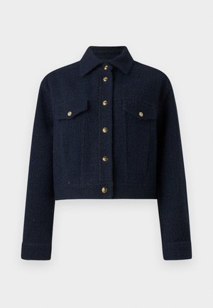 Veste courte bleu marine en tissu texturé avec un devant à boutons, deux poches poitrine et des boutons dorés. Dotée d'un col classique.