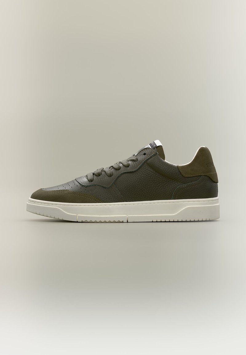 Baskets basses en cuir vert foncé avec semelle blanche, design à lacets et panneaux latéraux texturés, présentées de profil sur fond neutre.