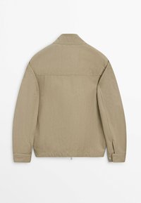 Giacca beige a maniche lunghe con colletto, cucitura posteriore dritta e polsini con bottoni, mostrata distesa da dietro su uno sfondo bianco.