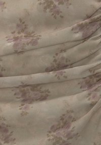 Tissu à motif floral dans un beige doux avec des fleurs roses et marron, présentant une surface texturée et un design subtil de drapé.