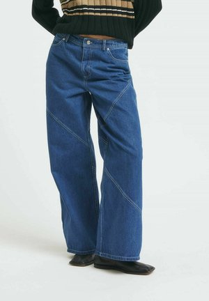 Jeans de denim azul de pierna ancha con detalles de costura diagonal, un diseño clásico de cinco bolsillos y un acabado de lavado medio.