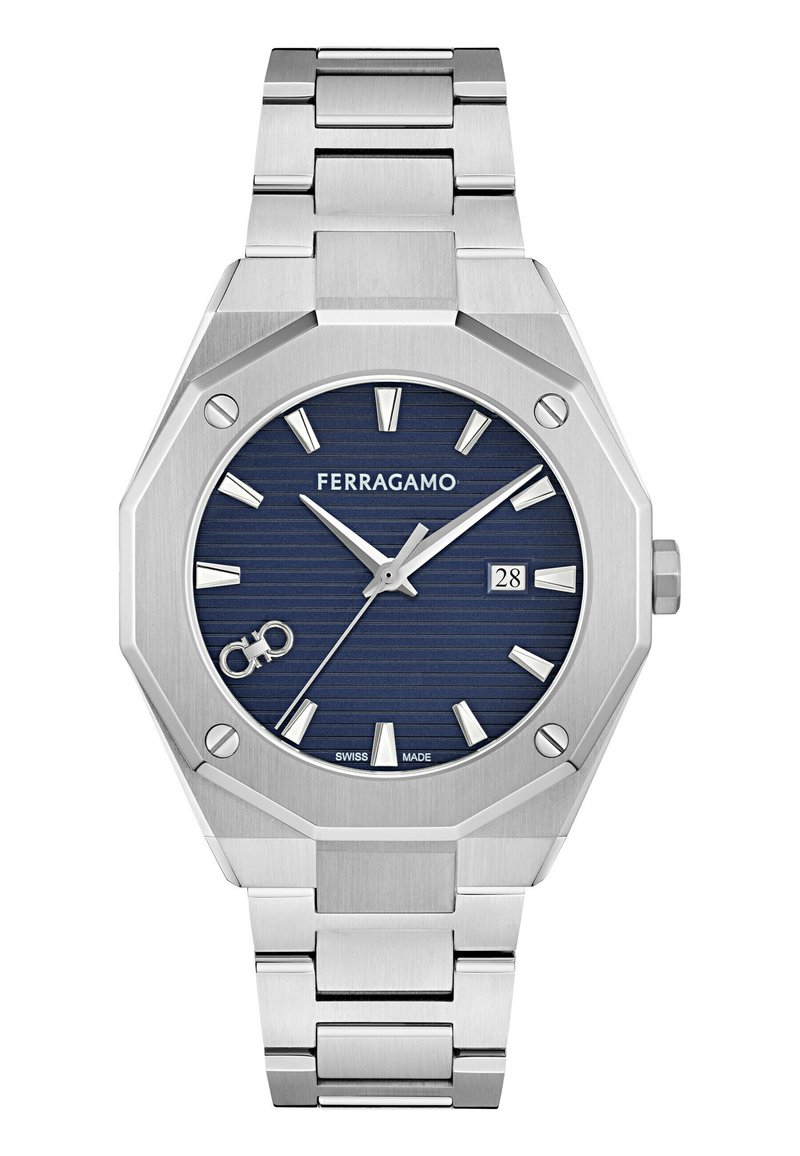 Reloj de acero inoxidable plateado con una caja octagonal, esfera texturizada de color azul marino, marcadores de hora plateados, pantalla de fecha y pulsera de eslabones. La marca "FERRAGAMO" es visible.
