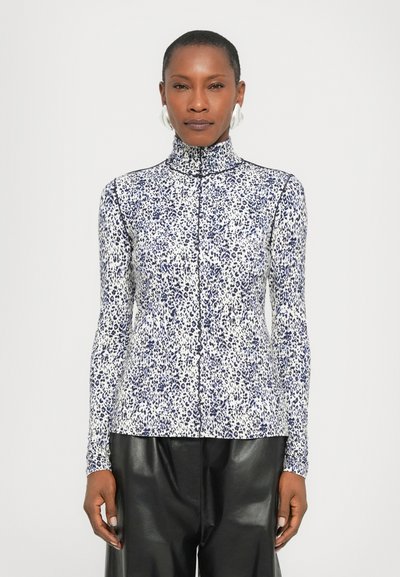 Long-sleeve, high-collar shirt in white with blue leopard print, made of stretchy fabric; features a central zipper and fitted design.