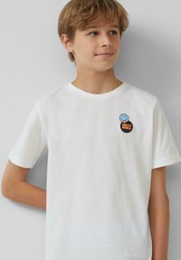 Witte T-shirt met korte mouwen van katoen, met een blauwe lachende gezicht en zwarte "SMILEY WORLD" grafieken op de borst.