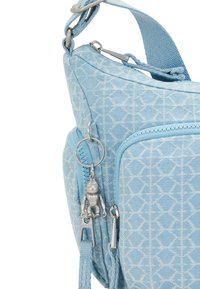 Light blue fabric bag with geometric pattern, featuring a zipper closure and a silver keychain accent. Adjustable strap for versatility.
