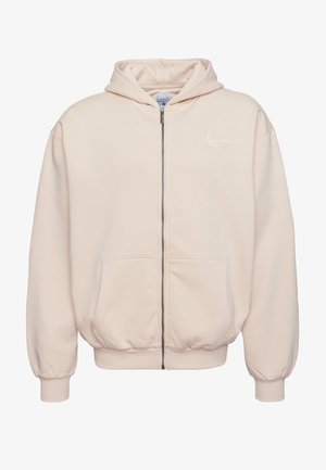 Light pink zip-up hoodie with a drawstring hood, front pockets, ribbed cuffs, and a small white logo on the left chest. Soft cotton material.