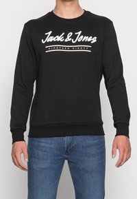 Sudadera negra de algodón, con cuello redondo, mangas largas y texto blanco con un detalle gráfico "Jack & Jones Nineteen Ninety."