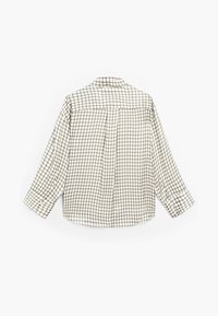 Chemise à manches longues avec un motif à carreaux beige et marron, vue de dos, étalée à plat sur un fond blanc.