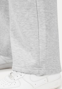 Gray sweatpants made of soft fabric, featuring a straight-leg design and cuffed hem, paired with white athletic sneakers.