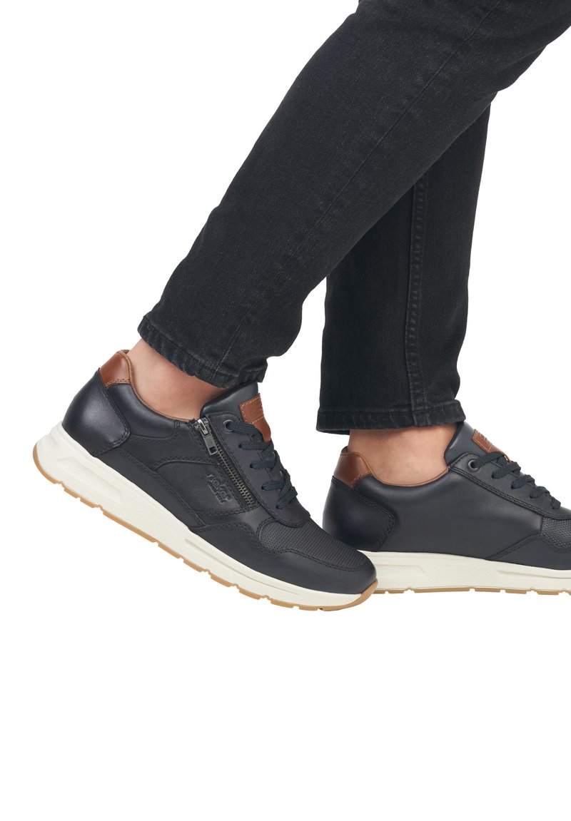 Donker marineblauwe leren sneakers met bruine accenten, voorzien van veters, een zijrits en een lichtgekleurde rubberen zool. Gevoed bovenmateriaal detail.