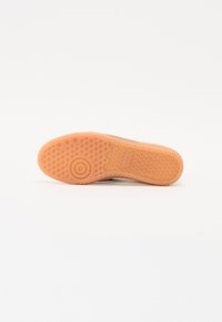 Világos narancssárga gumiból készült sneaker talp, texturált mintázattal, körkörös tapadás részlettel és sima élekkel, amelyek vonatkozó tapadást és támogatást nyújtanak.
