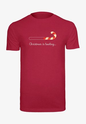 Rød bomulds T-shirt med et grafik af en slikstok og teksten "Jul er ved at indlæse..." i hvid skriftskrift. Korte ærmer.