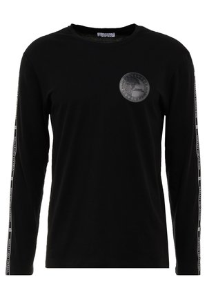 Musta pitkähihainen paita pyöreällä pääntiellä, Medusan tunnus vasemmassa rinnassa ja "Versace Collection" -teksti hihojen ulkoreunoilla.