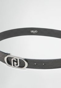 Must mustriba nahkemail koos reljeefse logo mustriga, hõbedase ovaalse pandlaga ja reguleeritavate aukudega. Pandla lähedal on märgistus "LIU•JO MILANO".