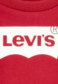 Tela roja con el logo de Levi's en blanco y rojo impreso cerca de un cuello acanalado.