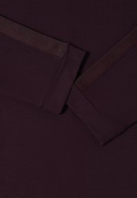 Bordowy długi rękaw z gładką fakturą, z kontrastującym błyszczącym akcentem wzdłuż rękawów.