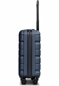 Valise rigide texturée bleu marine avec poignée télescopique noire déployée et quatre roues pivotantes noires vue de côté.