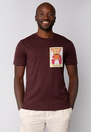 Bordeaux katoenen T-shirt met korte mouwen, met een kleurrijke grafische print van een koffiepot en wolken op de borst. Soepele textuur.