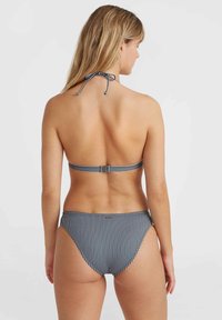 Striped bikini featuring a halter neck design with adjustable ties, back clasp closure, and low-rise bottoms. Colors are navy and white.