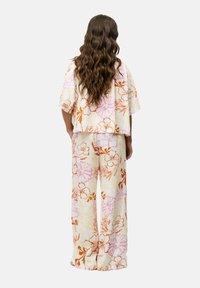 Floral loungewear set met een losse top en wijde broek. Stof in pastelkleuren van roze, geel en oranje met een gestructureerde afwerking.