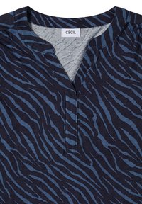 Haut bleu marine avec un motif zèbre en bleu clair. Présente un col en V et une coupe décontractée. Le matériau semble doux et texturé.