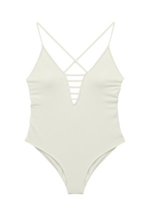 Costume intero bianco con texture, scollo a V profondo, dettagli con cinturini orizzontali sul petto e sottili spalline incrociate sulle spalle.