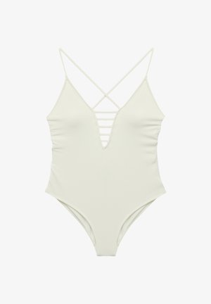 Costume intero bianco con texture, scollo a V profondo, dettagli con cinturini orizzontali sul petto e sottili spalline incrociate sulle spalle.