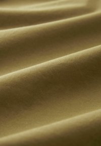 Țesătură texturată de culoare verde măslinie, cu o finisare netedă, având pliuri moi și subtile și o aparență mată. Fără modele sau accente vizibile.