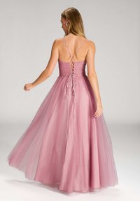 Maxi-jurk van zacht roze tule, met een aansluitende corsage en gekruiste banden, en een vloeiende rok. Lichtgewicht, doorschijnende textuur.