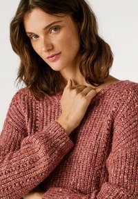 Στεγανωμένος ροζ πλεκτός πουλόβερ με άνετη εφαρμογή, με φαρδιές ριπ μανσέτες και λαιμό, που επιδεικνύει ένα σπιράλ σχέδιο νήματος.