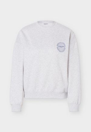 Világosszürke, kerek nyakú pulóver hosszú ujjakkal és kis kék kör alakú logóval a bal mellrészen, amelyen a „Björn Borg“ felirat olvasható.