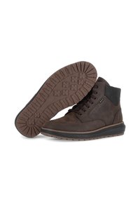 Braune Lederknöchelstiefel mit schwarzem gepolstertem Kragen, Schnürung vorne und rutschfester Gummisohle, ein Stiefel liegt auf der Seite und zeigt das Sohlenmuster.