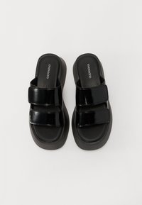 Black platform sandals featuring a glossy patent finish, two adjustable Velcro straps, and a textured footbed for comfort.